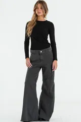 Jean de corte flare y tiro medio, confeccionado en denim negro con costuras verticales decorativas y ruedo deshilachado.