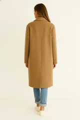 Tapado de corte recto y largo midi, confeccionado en tejido texturizado color gris. Presenta solapas clásicas, cierre frontal con botones y mangas largas.