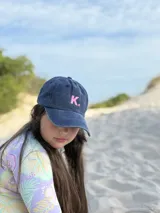 Gorra de gabardina color azul marino con efecto desgastado y bordado de la letra K en color rosa.