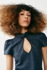 Vestido corto de denim azul con cuello mao, cierre tipo alamar en el pecho, mangas cortas abullonadas y fruncido lateral.