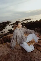 Blusa color gris con estampado floral blanco, cuello mao con lazo, mangas largas abullonadas con puños elásticos.