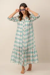 Vestido midi turquesa y blanco con estampado de rombos, cuello camisero, cierre frontal con botones y mangas cortas abullonadas. Cuenta con recortes fruncidos en la falda.