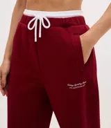 Pantalón deportivo de corte recto, confeccionado en tejido de microfibra color bordó. Presenta cintura elástica con cordón ajustable, bolsillos delanteros embutidos y detalle de bordado discreto en la pierna.