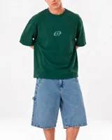 Remera oversize verde de tela rugby, con cuello redondo, mangas cortas y bordado frontal pequeño con diseño geométrico y la letra D.