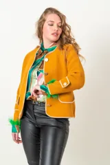 Chaqueta mostaza de tejido plano con vivos blancos, corte clásico y cierre frontal con botones dorados.