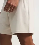 Bermuda deportiva color beige, con cintura elástica, cordón de ajuste, bolsillos con cierre y estampa lateral de lettering.