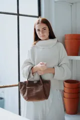 Mini bag de cuero marrón con textura tipo cocodrilo, diseño estructurado con cierre de broche metálico y doble asa corta.