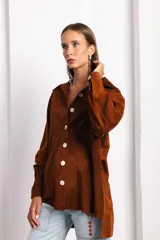 Camisa marrón de gamuza con botones blancos, cuello clásico y corte holgado.