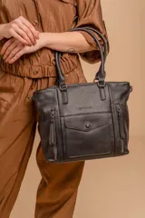 Cartera tipo tote de diseño estructurado en color marrón, confeccionada en cuero sintético con textura granulada. Cuenta con doble asa de mano, múltiples bolsillos frontales con cierre y un bolsillo central con solapa y botón a presión.