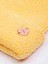 Gorro de lana color crema, tejido de punto con doblez en el borde inferior y parche circular con logo de la marca.