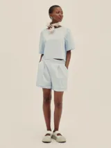 Shorts celestes a rayas verticales, de tiro alto y corte holgado, con pinzas en el frente y detalle de Polonio en cobre.