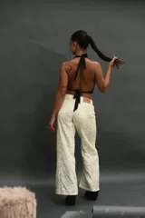 Top negro tipo halter, ajustado al cuerpo, con escote drapeado y detalles de ojales metálicos plateados a lo largo del borde del escote.