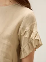 Blusa de lino color rosado, de corte recto y holgado, con cuello redondo y mangas cortas adornadas con volados.