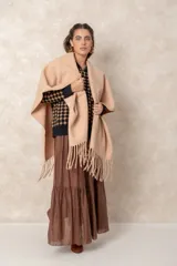 Ruana abierta de color beige, confeccionada en tejido de punto con terminación de flecos en el ruedo.