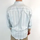 Camisa celeste con rayas verticales blancas, grises y beige. Tiene cuello italiano, manga 3/4 y corte semi entallado.