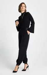 Sweater de tejido de punto fino con textura acanalada, color negro, de cuello alto y mangas largas con terminación acampanada.