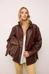 Chaquetón de cuero oversized color marrón, con corte recto, cuello camisero y cierre frontal de botones. Presenta bolsillos delanteros con bordados inspirados en la costa atlántica.