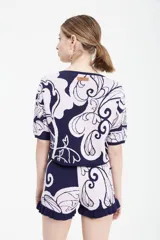 Top tejido en jacquard azul y beige con estampado floral, corto a la cintura, de calce oversize en cuerpo y más entallado en mangas, con escote redondo.