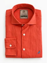 Camisa de lino color naranja, de corte slim fit, con cuello camisero, manga larga y detalle de ave bordada en contraste en el bajo.