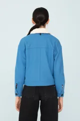 Chaqueta azul con bolsillos delanteros forrada, botones metálicos y cuello desmontable con corderito.