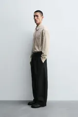 Camisa de corte relajado confeccionada en algodón, con estampado de rayas verticales. Presenta cuello solapa, manga larga con puños abotonados, bolsillo frontal y corbata integrada del mismo tejido.