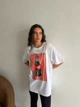 Remerón de algodón blanco con corte oversize y cuello redondo, que presenta un estampado frontal con diseño de una lata de sardinas sobre fondo de rayas.