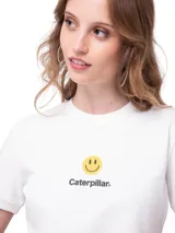 Remera crop blanca de algodón y poliéster reciclado, de manga corta y cuello redondo. Presenta un estampado frontal con una carita feliz y el texto "Caterpillar".