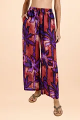 Pantalón de corte amplio y tiro alto con cintura elástica y cordón ajustable. Presenta un estampado botánico de hojas en tonos púrpuras y rojizos sobre una base cobriza, con una caída fluida y relajada.