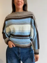 Sweater de tejido de punto con diseño de rayas horizontales en tonos celeste, blanco, gris y marrón. Presenta cuello redondo, mangas tipo murciélago y puños y pretina acanalados.
