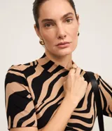 Blusa de manga corta y cuello alto, confeccionada en viscosa con elastano, con estampado animal print de cebra y textura acanalada tipo rib.