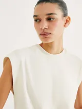 Camiseta sin mangas de tejido de punto fino, color gris claro, con cuello redondo y hombreras sutiles que aportan estructura.