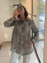 Campera tipo gamulán de cuero genuino con efecto desgastado, cuello de corderito y cierre frontal con botones.