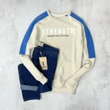 Buzo color arena con mangas ranglan azul eléctrico y estampa frontal con la palabra "Strength" y la frase "Duxon Collection".