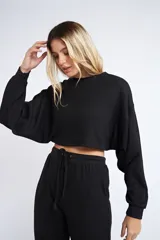 Buzo corto de tejido rib en color verde militar, con mangas largas y cuello redondo. Presenta un diseño holgado y cropped.