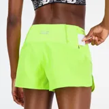 Short deportivo color verde flúor con cintura elástica y logo reflectivo de New Balance en la pierna izquierda.