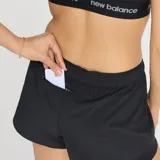 Short deportivo New Balance para mujer, color negro, con calza interior ajustada y short exterior holgado. Cuenta con tecnología NB DRY para absorción de la humedad, bolsillos internos y bolsillo trasero con cremallera.