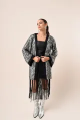 Kimono corto con estampado de rayas plateadas y negras, mangas campana con puños negros y flecos negros en el dobladillo.