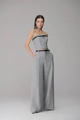 Pantalón de vestir de corte recto y tiro alto, confeccionado en tela gris con nervuras frontales que estilizan la silueta. Presenta bolsillos laterales y cierre frontal, con un diseño estructurado y elegante.