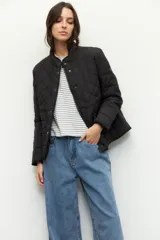 Campera capitoneada de color negro con cuello alto, cierre frontal mediante botones metálicos a presión y bolsillos laterales.