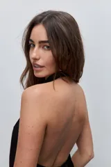 Top negro de cuello drapeado con espalda descubierta y calce fluido.