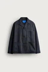 Sobrecamisa de algodón de corte relajado, color negro con efecto gastado, cuello con solapas de muesca, mangas largas raglán y cierre frontal con botones. Cuenta con bolsillos frontales de plastrón en el pecho y en la parte inferior.