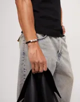 Pulsera de cuero tubular trenzado color negro, con cierre de metal plateado.