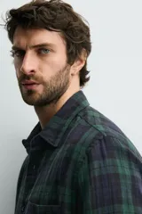 Camisa de corte regular fit confeccionada en tejido doble de algodón, con diseño de cuadros en tonos verde y azul marino. Presenta cuello solapa, manga larga con puño abotonado, bolsillo plastrón en el pecho y cierre frontal con botones.