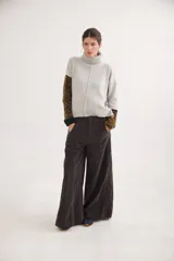 Polera de calce relajado con cuello alto, confeccionada en lana. Presenta un diseño bicolor con cuerpo en gris claro y mangas con estampado jacquard de arabescos en tonos tierra y negro. Incluye detalle de costura central vertical en el frente.