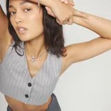 Collar de plata con cadena de bolitas y un dije central con forma de corazón irregular. El cierre tiene un pequeño dije con el logo grabado.