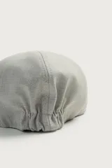 Boina con visera de color beige y marrón con diseño de cuadros pequeños, confeccionada en tejido con viscosa y ajuste elástico posterior.