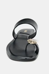 Sandalia plana negra con tira ancha en el empeine y tira para el dedo con detalle de abalorio metalizado. Suela cuadrada.