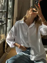 Camisa básica de corte oversize confeccionada en crepé de seda, con cuello clásico, cierre frontal de botones y mangas largas con puños.