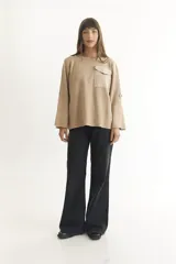 Sweater color beige de tejido de punto, con cuello redondo, manga larga con botón decorativo y bolsillo de parche en el pecho.