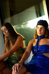 Vestido corto negro con diseño cut-out en la cintura, estilo strapless y ruedo decorado con flecos largos.